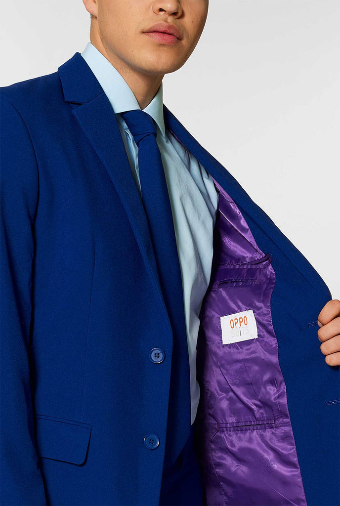 Marineblauw massief gekleurd pak gedragen door de mens met een jas
