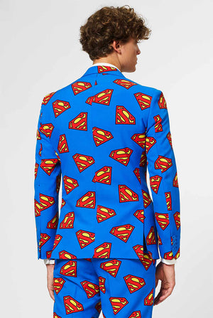 Man draagt ​​blauw herenpak met Superman -logo -print, bekijk vanaf de achterkant