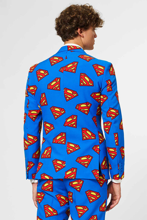 Man draagt ​​blauw herenpak met Superman -logo -print, bekijk vanaf de achterkant
