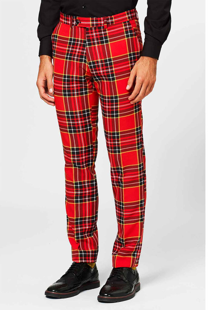 Man draagt ​​een rood kersttartan herenpak, broek van dichtbij