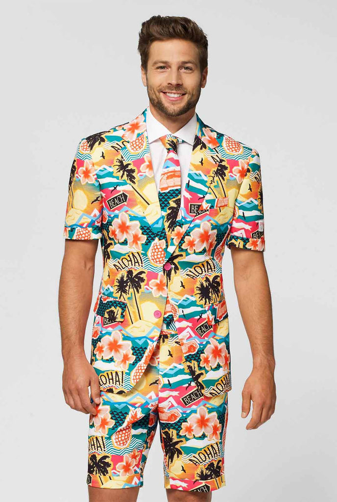 Man draagt ​​een kleurrijk Hawaiiaans print zomerpak, bestaande uit korte, jas en stropdas