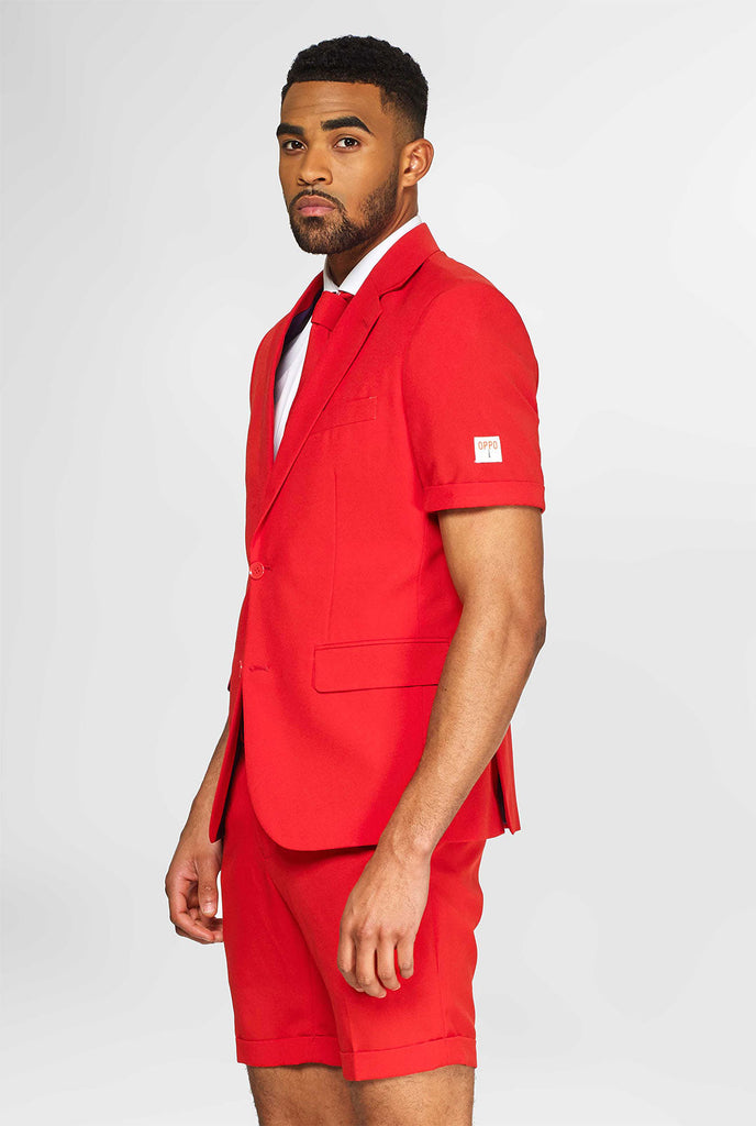 Man draagt ​​een rood zomerpak, bestaande uit shorts, jas en stropdas