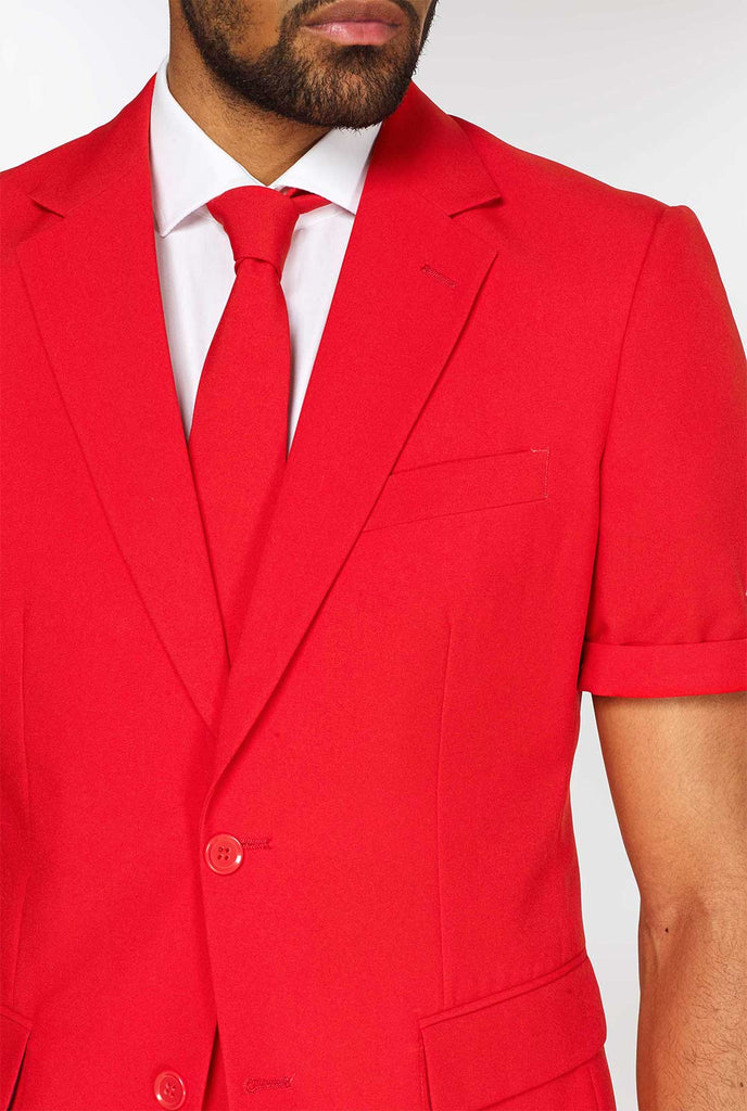 Man draagt ​​een rood zomerpak, bestaande uit shorts, jas en stropdas, close -up