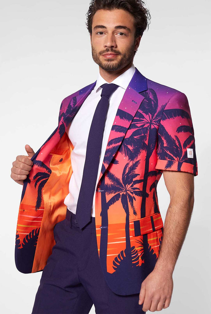 Man draagt ​​zomerpak met palmen en zonsondergangprint