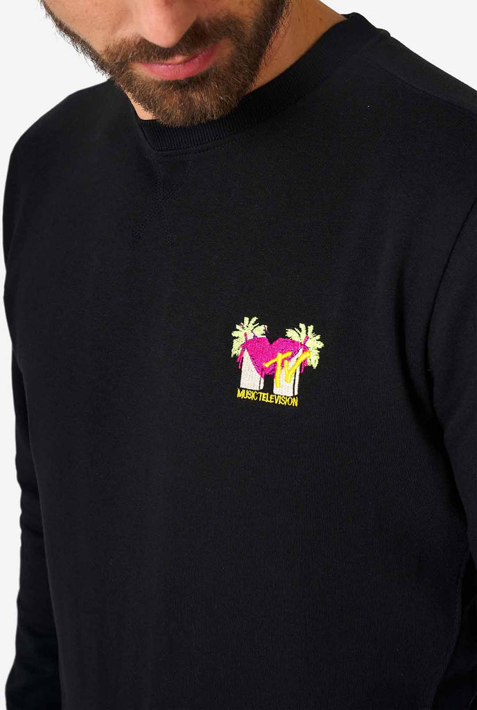 Man draagt ​​een zwarte trui met MTV -borduurwerk, close -up