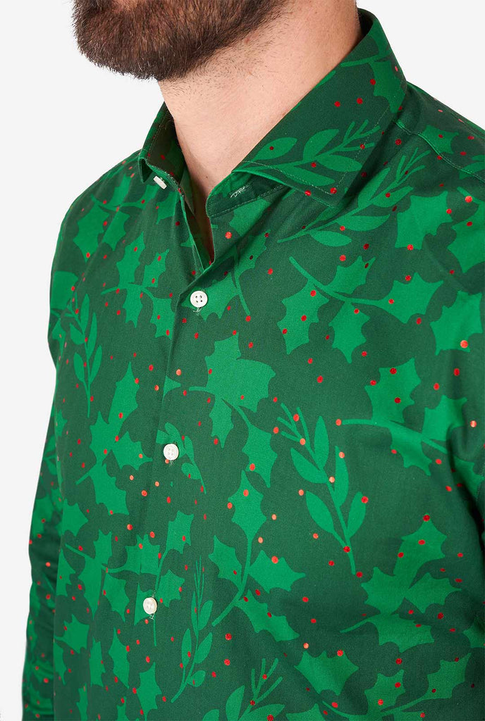 Man draagt ​​groene kerst overhemd met hulst- en maretak -print, close -up