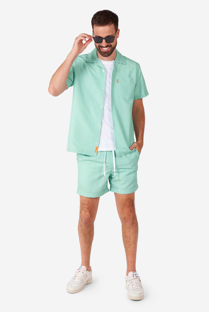 Man draagt ​​een groene zomerset, bestaande uit shirt en shorts met korte mouwen.