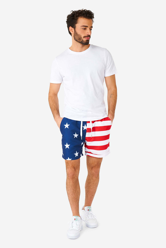 Man draagt ​​zomeroutfit, bestaande uit shirt en shorts, met de Amerikaanse vlaggenprint