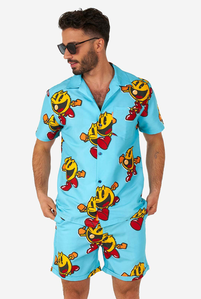 Man draagt ​​een blauwe zomerse shorts en shirt, met pac-man print