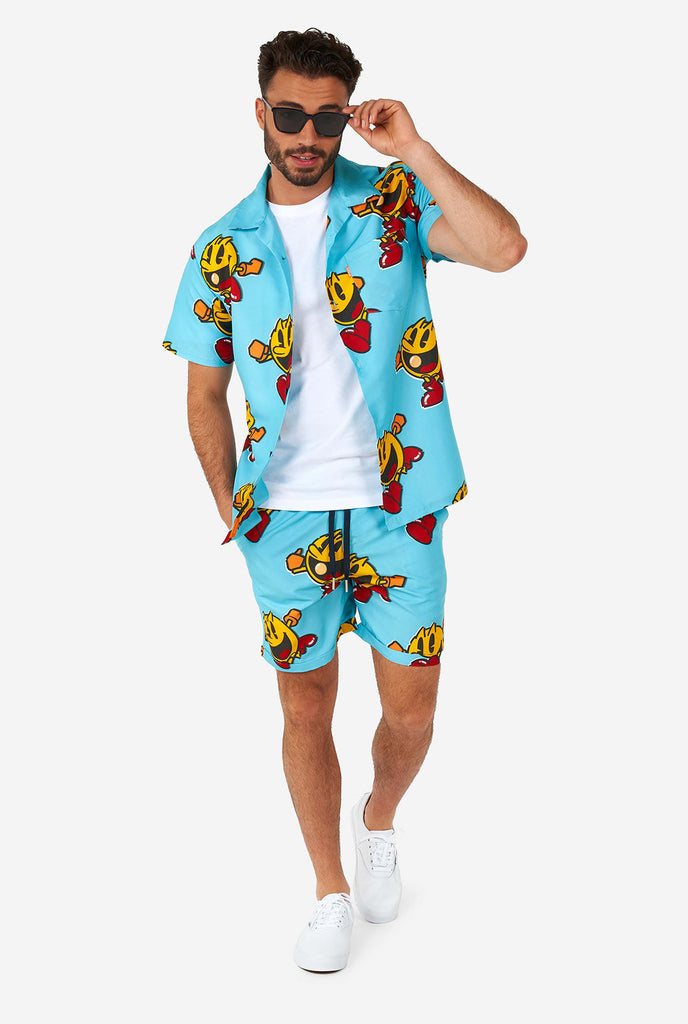 Man draagt ​​een blauwe zomerse shorts en shirt, met pac-man print