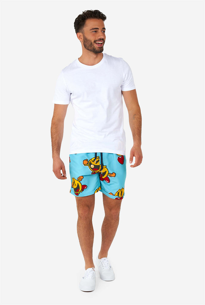 Man draagt ​​een blauwe zomerse shorts en shirt, met pac-man print