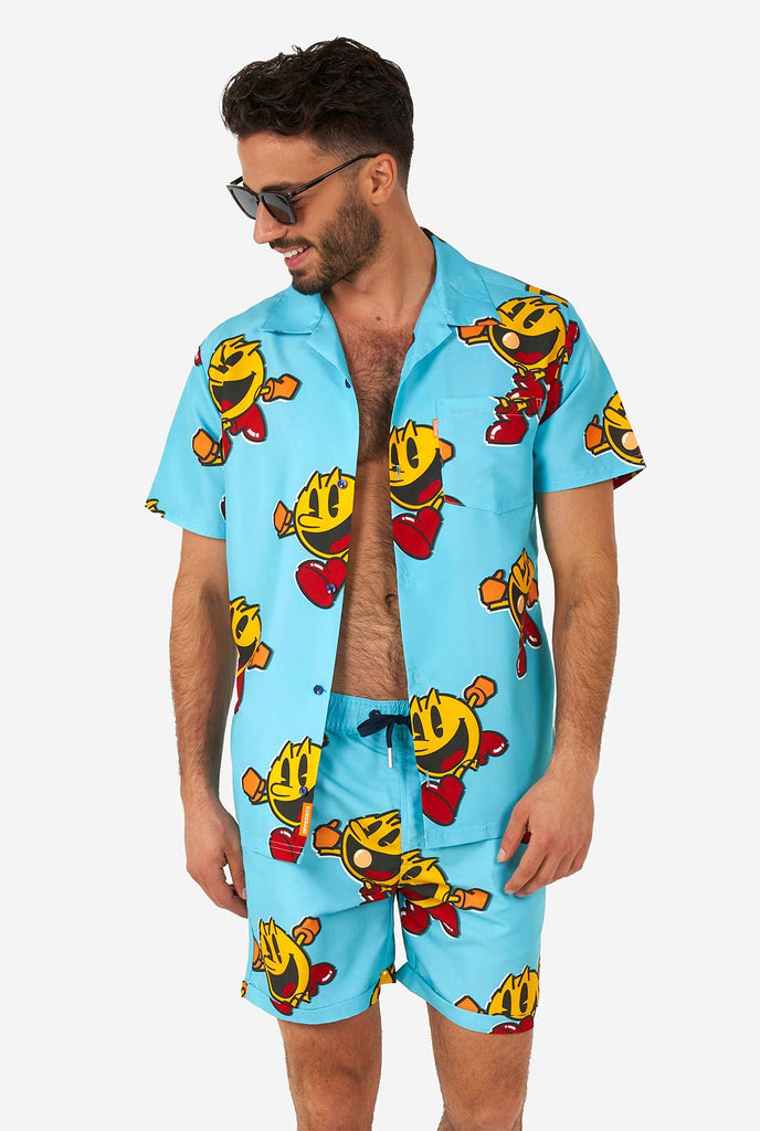Man draagt ​​een blauwe zomerse shorts en shirt, met pac-man print