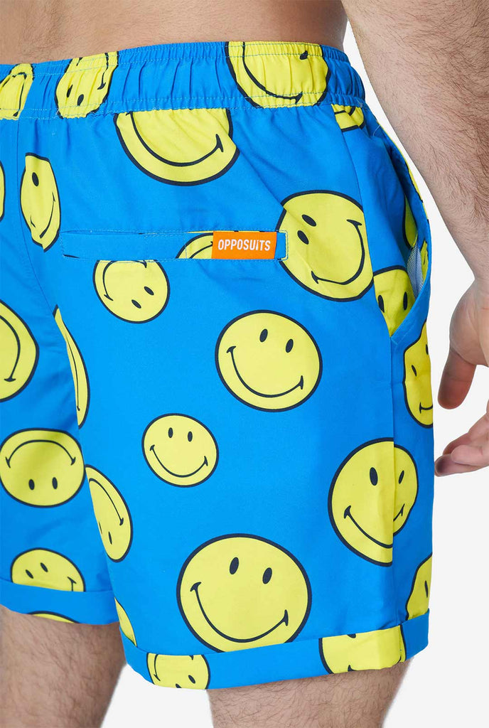 Man draagt ​​een blauwe zomerset, bestaande uit shorts en shirt, met smileyprint, shorts close -up