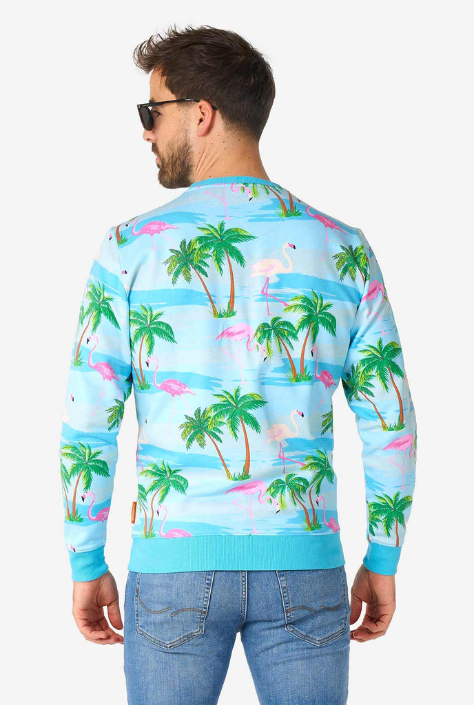 Man draagt ​​een blauwe trui met tropische flamingo -print, bekijk vanaf de achterkant