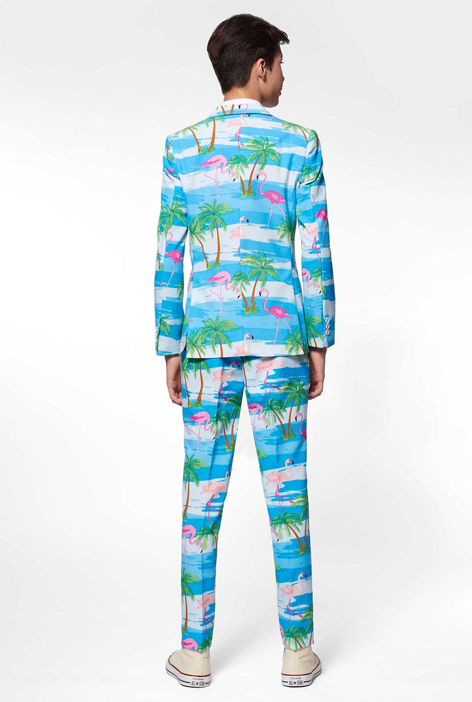 Tiener draagt ​​een lichtblauw pak met flamingo palmboomprint, bekijk vanaf de achterkant
