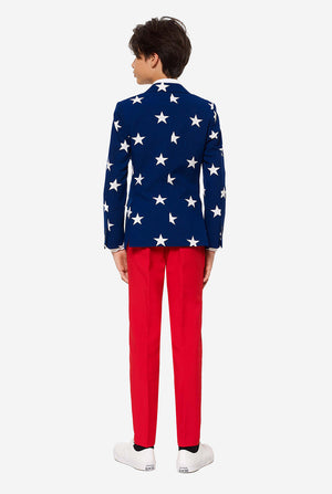 Tiener draagt ​​een formeel pak met de VS op het vierde juli, bestaande uit blauwe jas en rode broek.