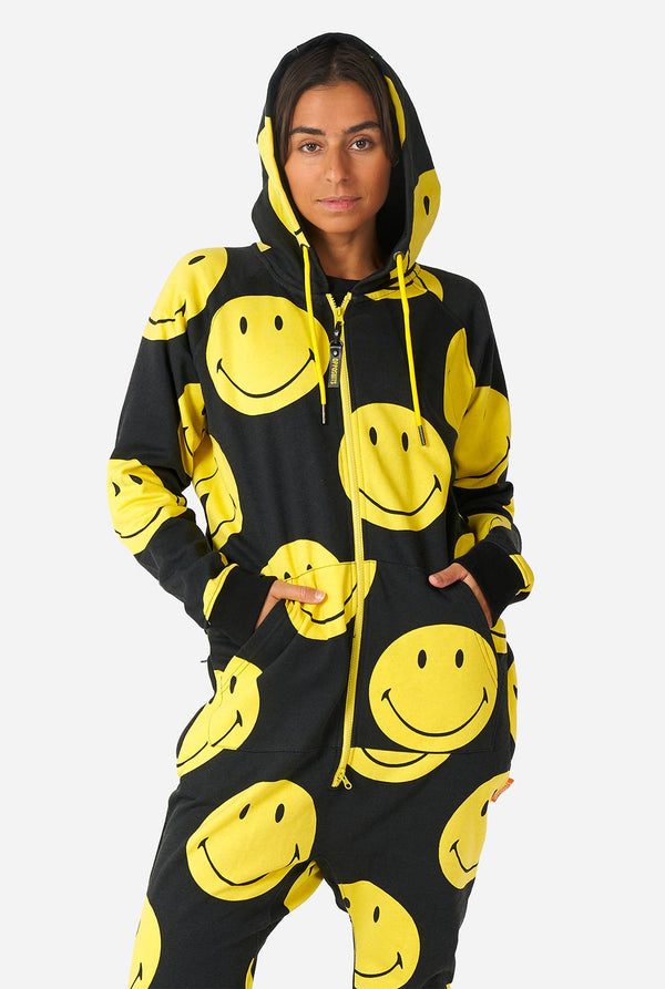 Vrouw draagt ​​zwarte onesie met gele smileyprint